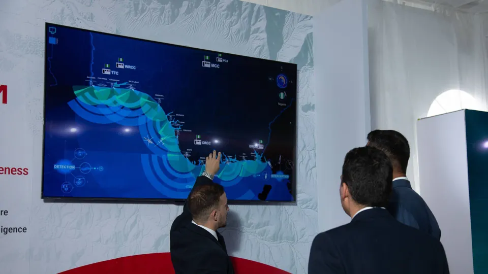 Touchscreen demonstration - Visitors explore a blue technical visualization on a large screen.