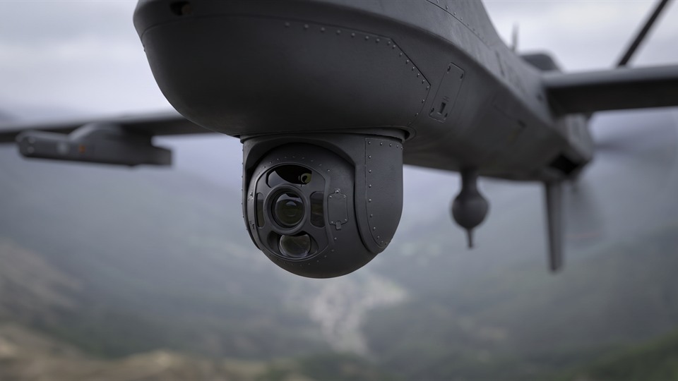 A multi-lens sensor beneath an unmanned aircraft.